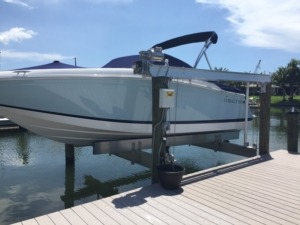 An aluminum direct drive assembly boat lift next to a stationary dock on the water