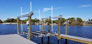 An aluminum boat lift with direct drive assembly next to a stationary dock set up for a tri-toon boat